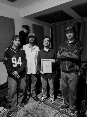 Integrantes da banda Noahs no estúdio de ensaio, um deles segurando o certificado de marca registrada